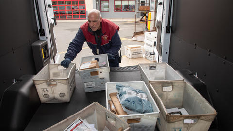 Mail delivery driver sorting through packages